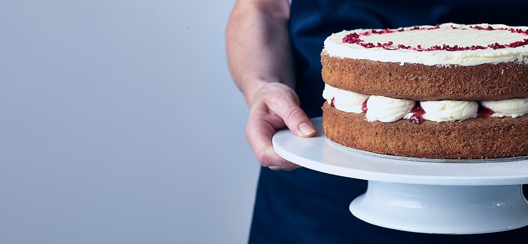 Baker holding victoria sponge cake